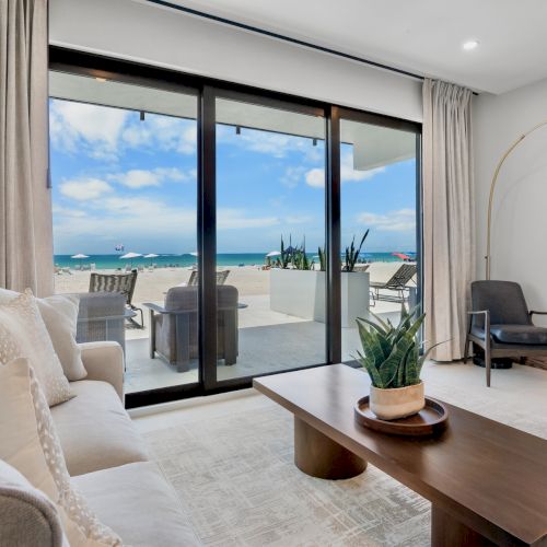 A bright, modern living room with a large window view of a balcony and cityscape; light sofa, coffee table, and contemporary decor.
