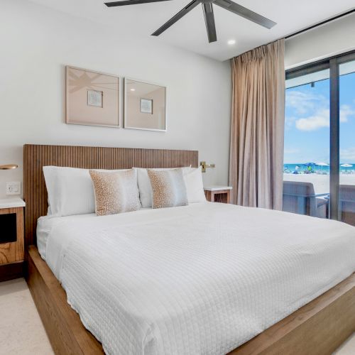A bright hotel room with a large bed, two nightstands, a desk, and a window view of a city skyline. Top it at 140 characters, always ending the sentence.